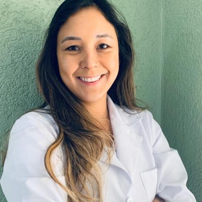 Médica sorrindo com jaleco branco em consultório